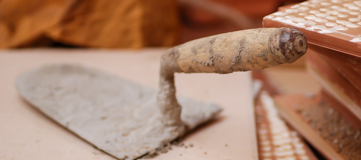 Maurerkelle mit Holzgriff auf frisch verlegten Fliesen