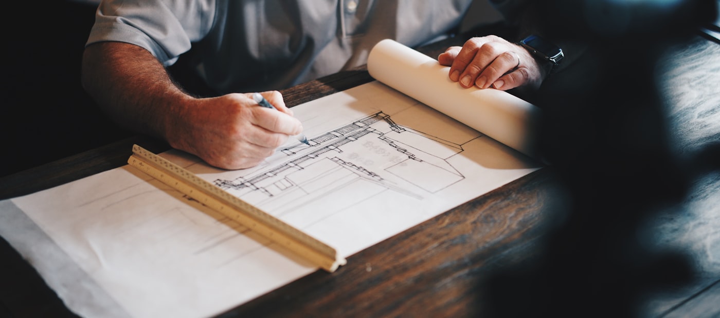 Architekt zeichnet einen Bauplan mit Zollstock am Zeichentisch
